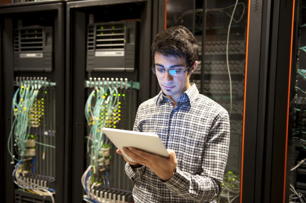 An IT technician programming computer equipment in a server room