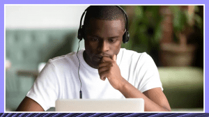 African American student wearing headphones looking pensively at his laptop.