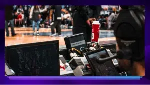 A sports analyst collects data during a basketball game.